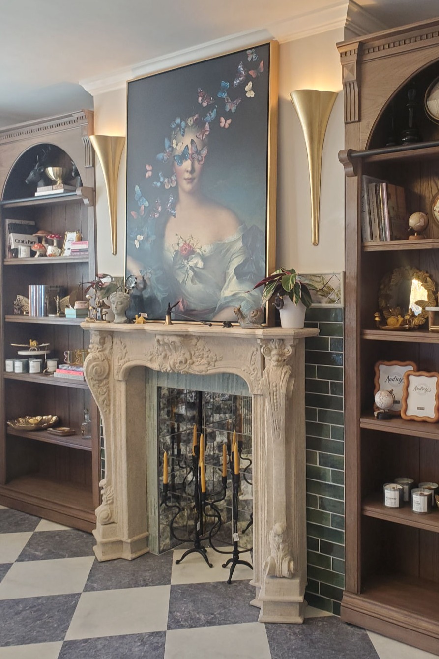 Decorative mantelpiece featuring large artwork, gold sconces, and checkered flooring
